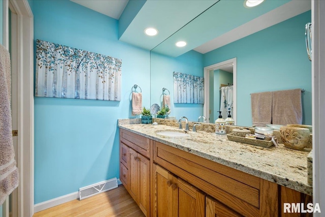 bathroom with recessed lighting, wood finished floors, vanity, visible vents, and baseboards