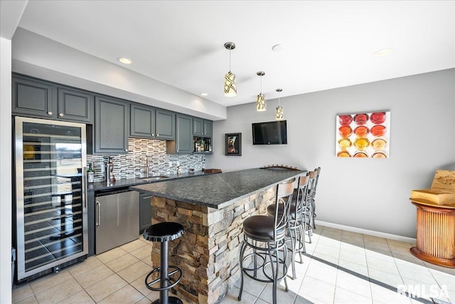 kitchen featuring dark countertops, wine cooler, refrigerator, a kitchen bar, and backsplash