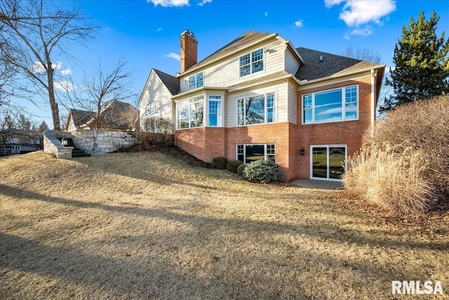 rear view of property with brick siding and a chimney