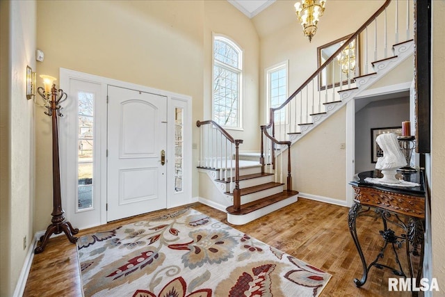 foyer entrance with a towering ceiling, stairway, baseboards, and wood finished floors