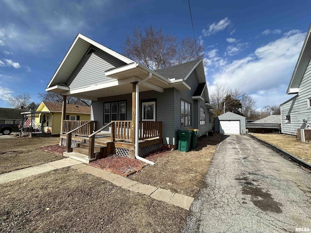 bungalow-style house featuring roof with shingles, covered porch, a garage, driveway, and an outdoor structure