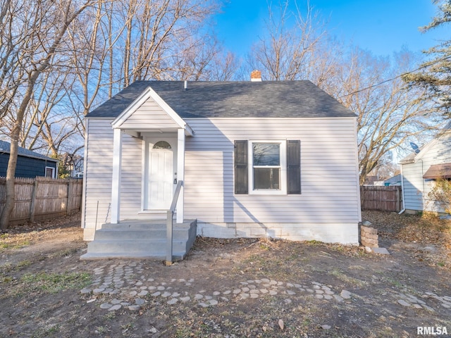 view of front of home with a chimney, fence, and roof with shingles