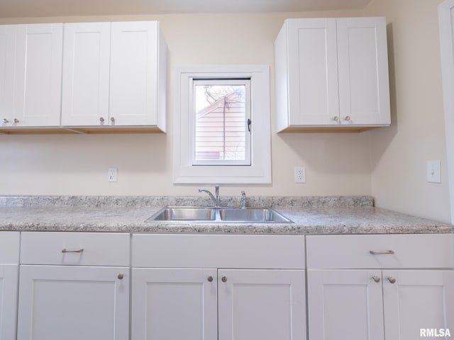 kitchen with light countertops, a sink, and white cabinetry