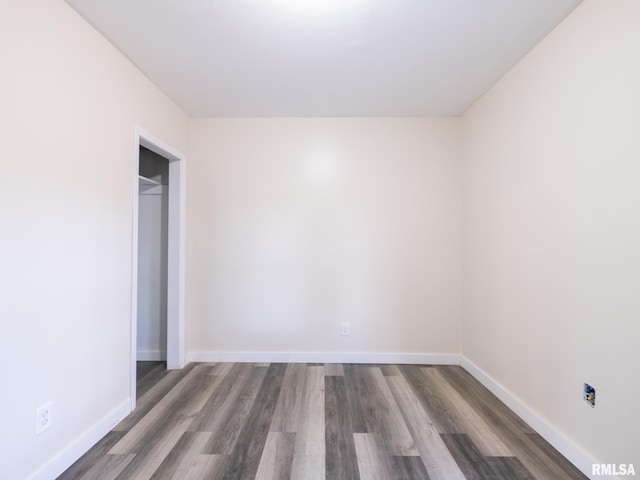 spare room with baseboards and wood finished floors