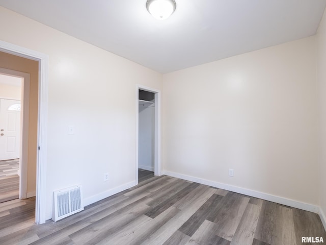 unfurnished bedroom with a closet, visible vents, baseboards, and wood finished floors