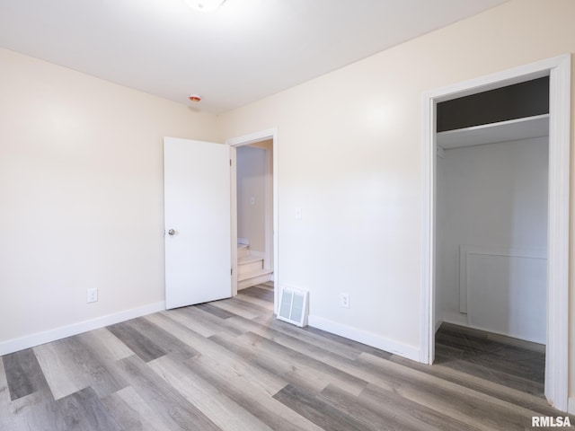 unfurnished bedroom featuring light wood-style flooring, visible vents, baseboards, a spacious closet, and a closet