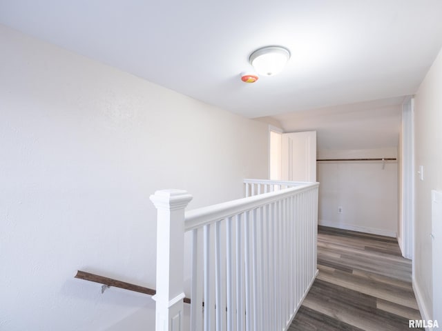 corridor featuring baseboards, wood finished floors, and an upstairs landing