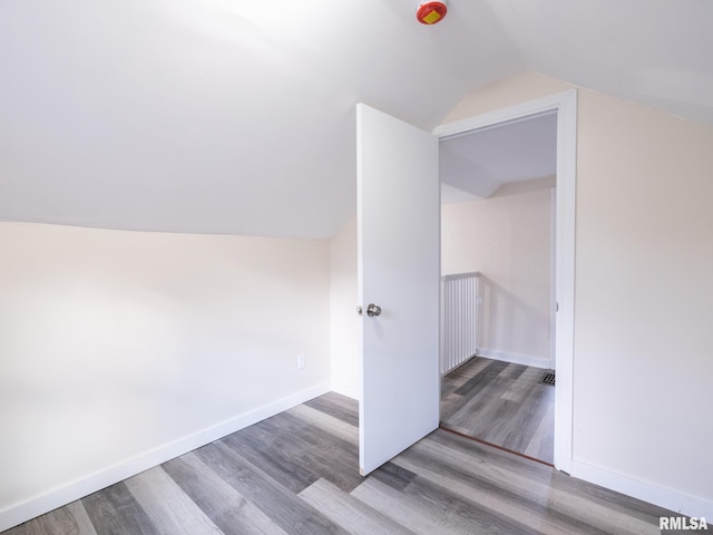 additional living space with vaulted ceiling, baseboards, and wood finished floors