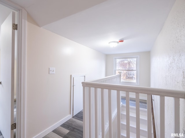 hall featuring dark wood-style floors, an upstairs landing, and baseboards