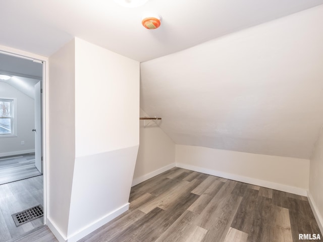 interior space featuring visible vents, baseboards, vaulted ceiling, and wood finished floors