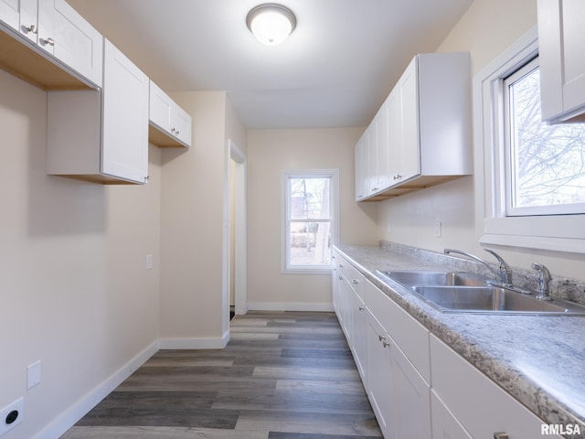 kitchen featuring dark wood-style flooring, a sink, white cabinetry, and baseboards