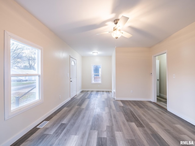 unfurnished living room with baseboards, visible vents, ceiling fan, and wood finished floors