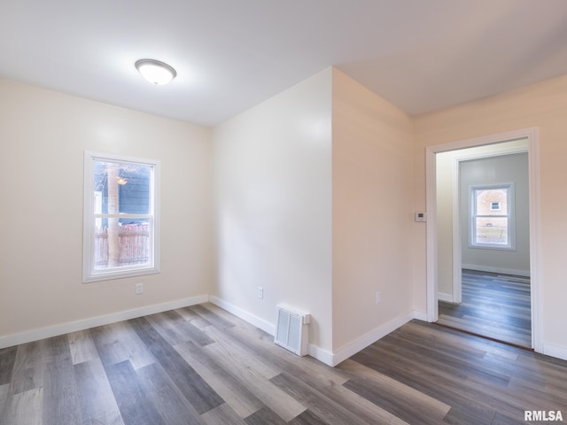 empty room with baseboards, visible vents, and wood finished floors