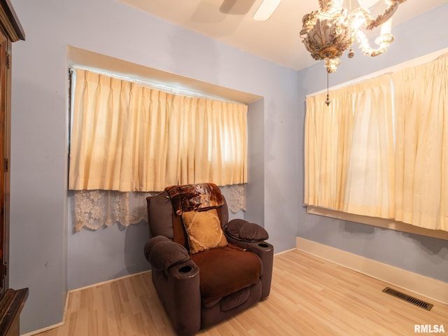 sitting room with baseboards, visible vents, wood finished floors, and ceiling fan with notable chandelier