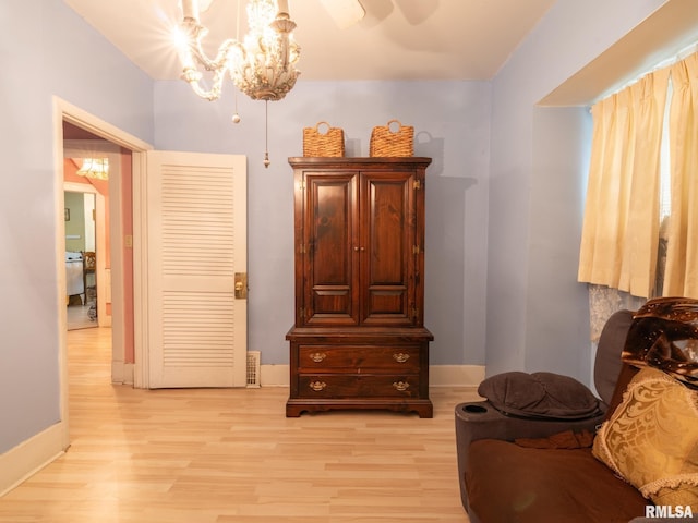 sitting room with an inviting chandelier, light wood-style flooring, and baseboards