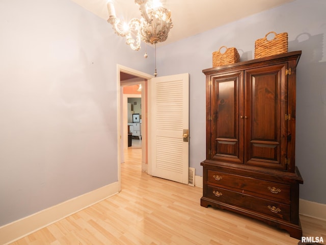 hall featuring light wood-style floors, a chandelier, and baseboards