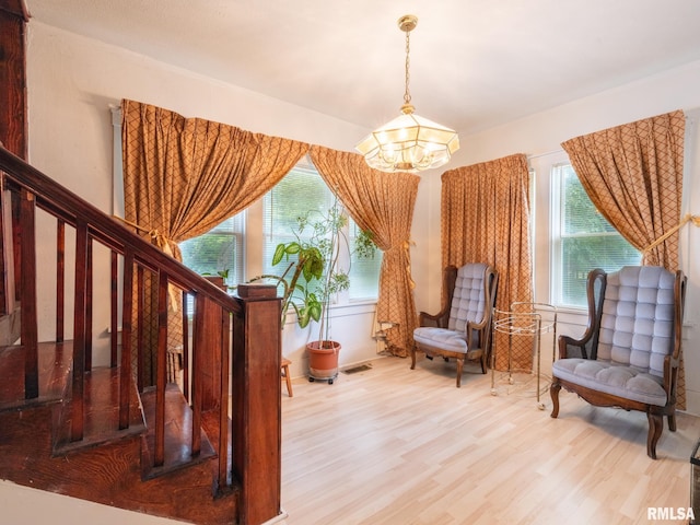 living area featuring stairs, plenty of natural light, wood finished floors, and a notable chandelier