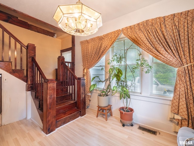 stairs featuring visible vents, a chandelier, and wood finished floors