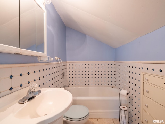 full bath with lofted ceiling, a garden tub, tile patterned flooring, toilet, and a sink