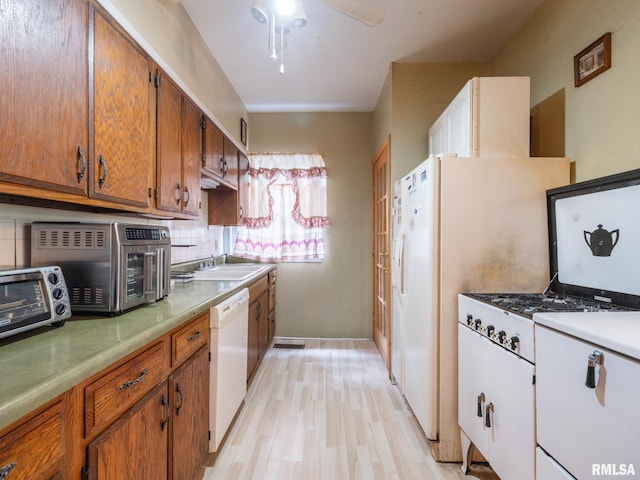 kitchen with white dishwasher, a sink, light wood-style floors, light countertops, and brown cabinetry