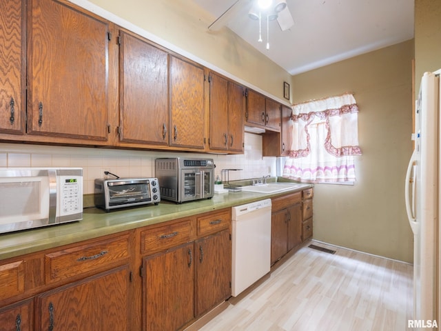 kitchen with white appliances, tasteful backsplash, visible vents, and a sink