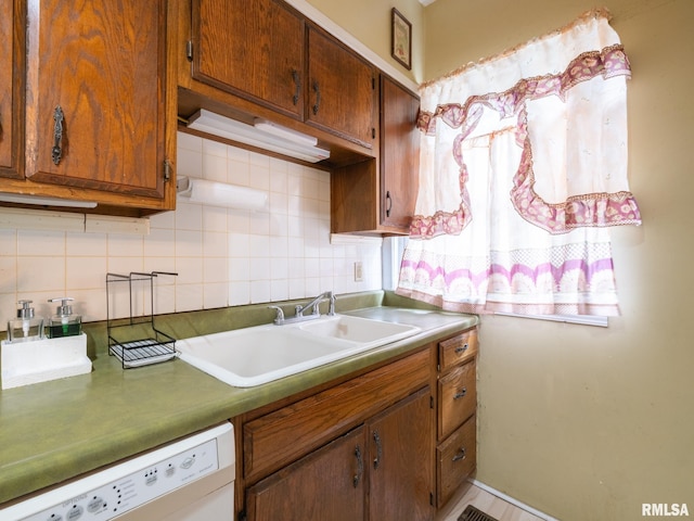 kitchen with dishwasher, brown cabinets, a sink, and decorative backsplash