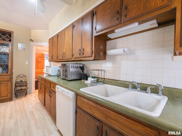 kitchen with white appliances, tasteful backsplash, brown cabinets, light wood-style floors, and a sink