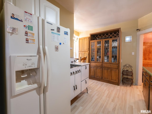 kitchen with light wood finished floors and white refrigerator with ice dispenser