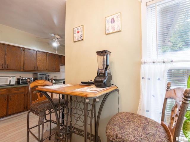 kitchen with light wood-style floors, brown cabinets, ceiling fan, and white microwave