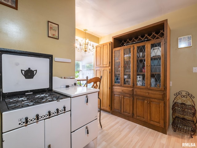 kitchen with pendant lighting, brown cabinets, light countertops, an inviting chandelier, and light wood-style floors