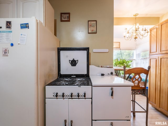 kitchen with light wood finished floors, light countertops, a notable chandelier, and freestanding refrigerator