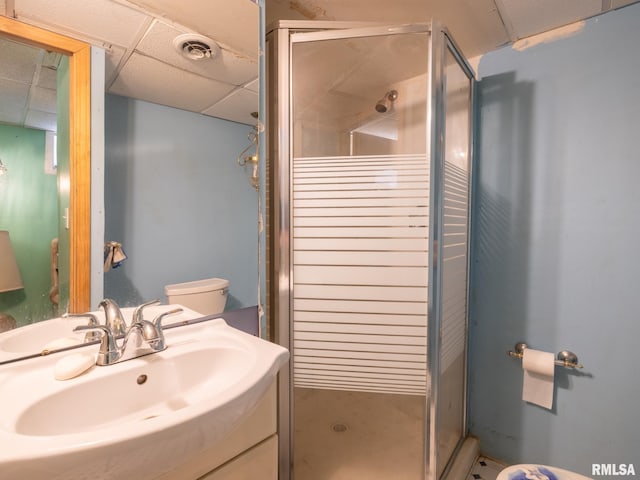 bathroom featuring a drop ceiling, toilet, vanity, visible vents, and a shower stall