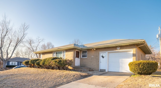 single story home with driveway, brick siding, and an attached garage