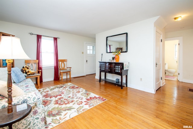 living area featuring light wood finished floors, baseboards, and visible vents