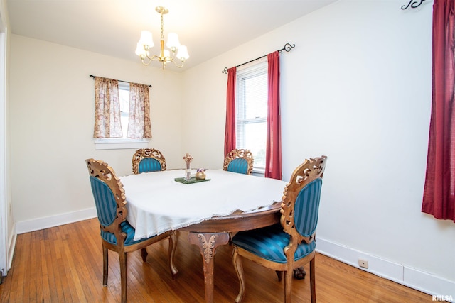 dining space with a wealth of natural light, light wood-type flooring, a chandelier, and baseboards