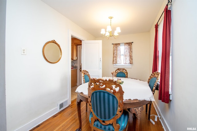 dining space with a chandelier, light wood finished floors, visible vents, and baseboards