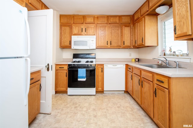 kitchen with white appliances, light countertops, and a sink