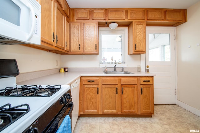 kitchen with white appliances, light countertops, a sink, and brown cabinetry