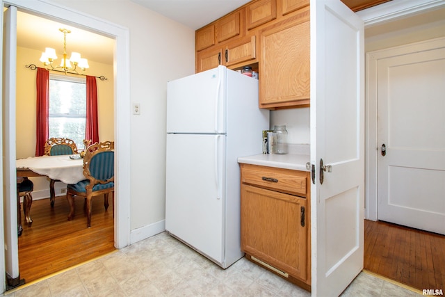 kitchen featuring baseboards, a chandelier, light countertops, and freestanding refrigerator