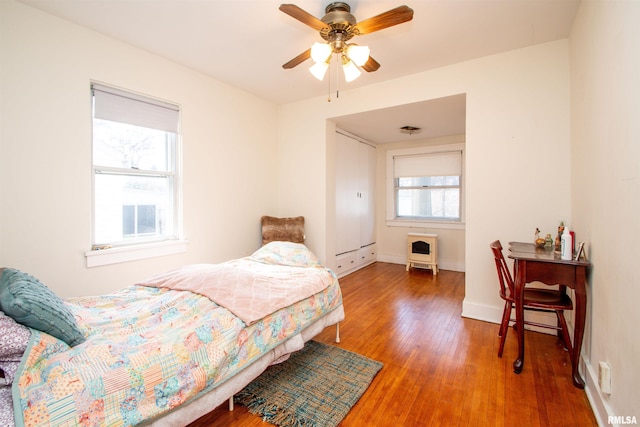 bedroom with wood-type flooring, a ceiling fan, and baseboards