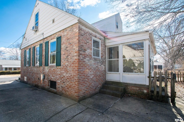 view of home's exterior with brick siding, cooling unit, and a sunroom