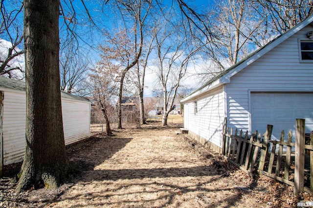 view of yard featuring a garage, fence, and an outdoor structure