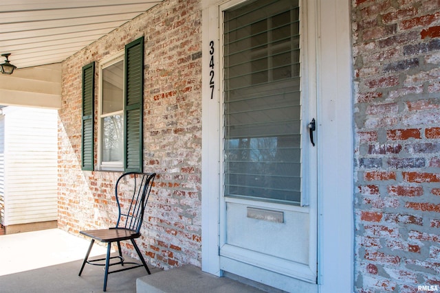 view of exterior entry with covered porch and brick siding