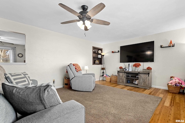 living room with wood finished floors, a ceiling fan, and baseboards