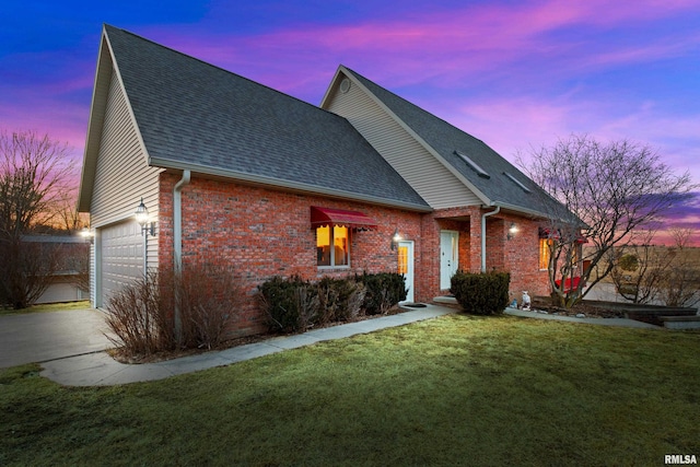 view of front of house with driveway, a yard, a shingled roof, and brick siding