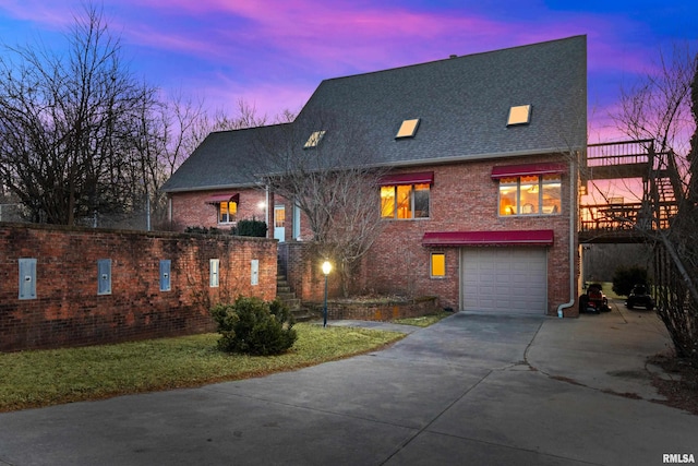 view of front of house with an attached garage, roof with shingles, concrete driveway, and brick siding