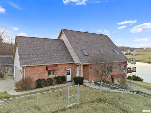 view of front facade featuring a shingled roof, a gate, brick siding, and a fenced front yard