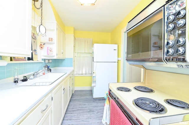 kitchen featuring white appliances, tasteful backsplash, white cabinets, and light countertops