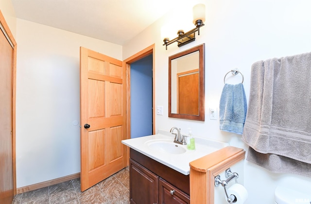 bathroom with baseboards, vanity, and toilet