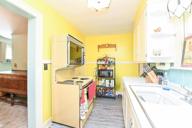 kitchen featuring light countertops, electric range, white cabinetry, a sink, and black microwave